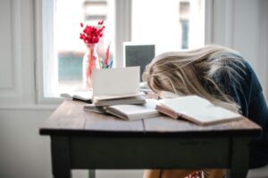 woman slumped over desk procrasting